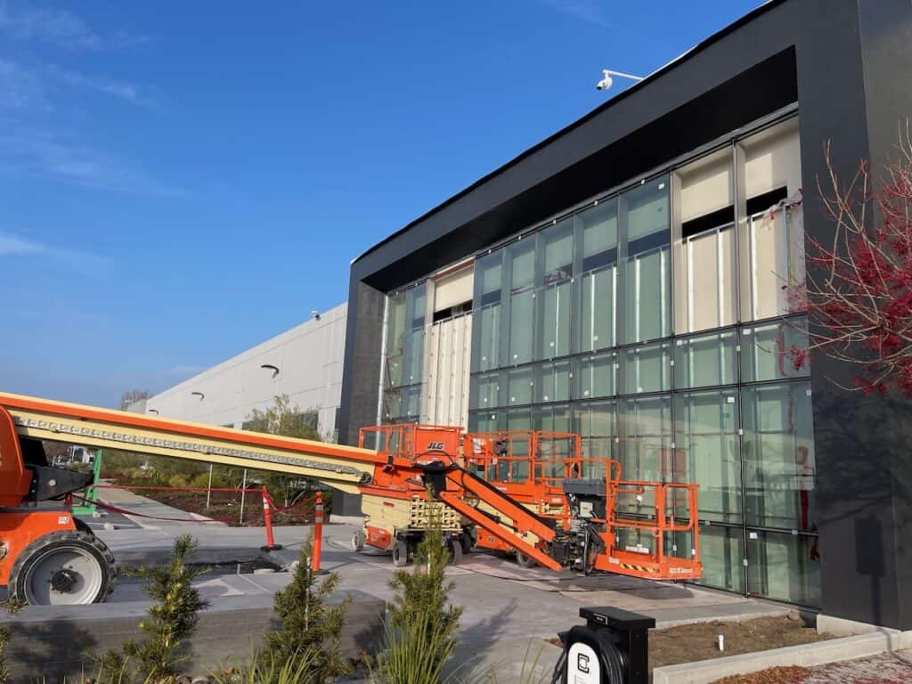 Commercial building facade being glazed with lifts on site