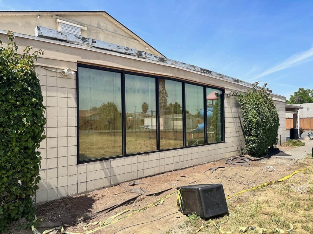 Newly installed black framed storefront windows along the exterior of a single story commercial building
