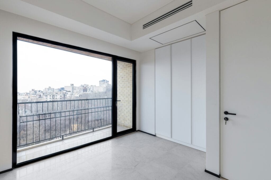 Empty room with a large picture window opening onto a balcony