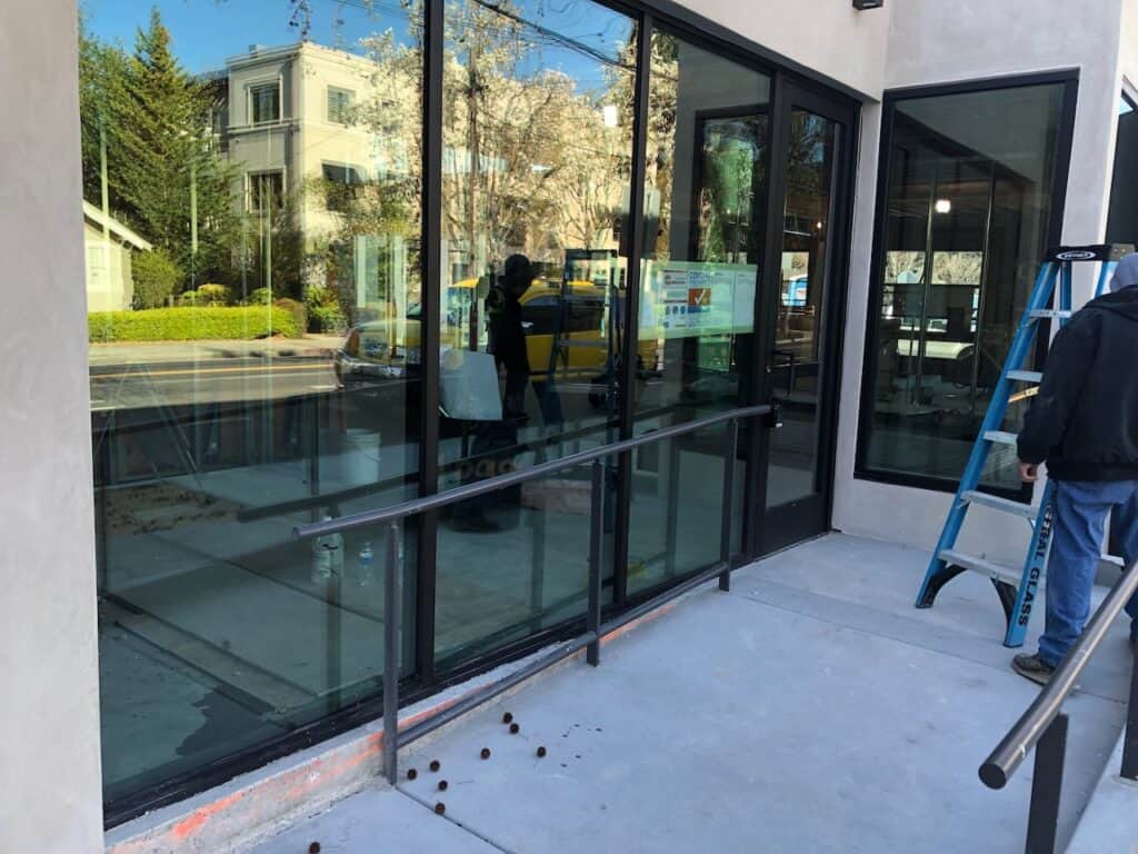 Glazier on a ladder working on commercial glass entry doors