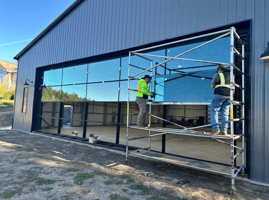 Glaziers installing a large glazed door system from scaffolding