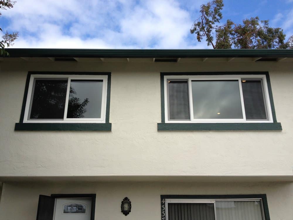 Two black framed windows in a rendered exterior wall