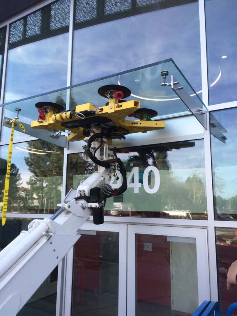 Vacuum lifter holding a glazed panel during a storefront installation
