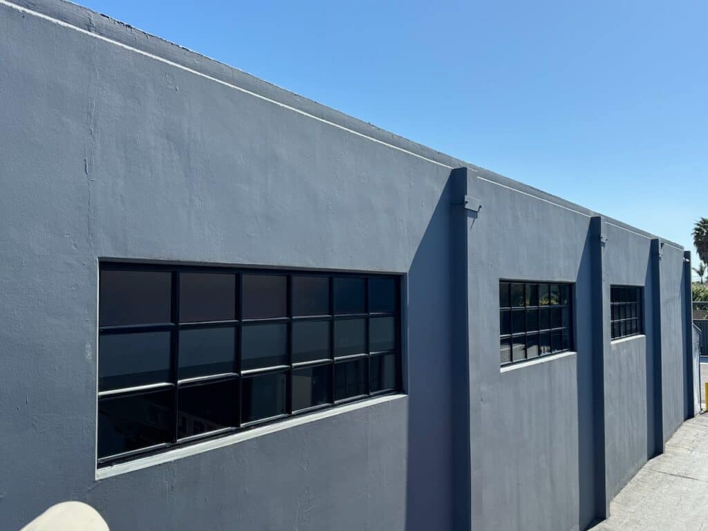 Row of dark framed replacement windows along a warehouse exterior